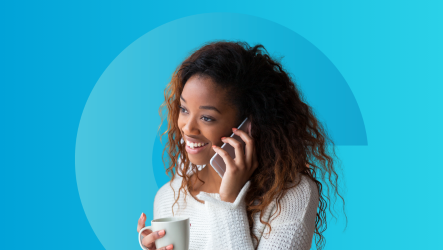 Mortgage broker smiling while using phone and coffee cup — representing energy, balance, and client connection.